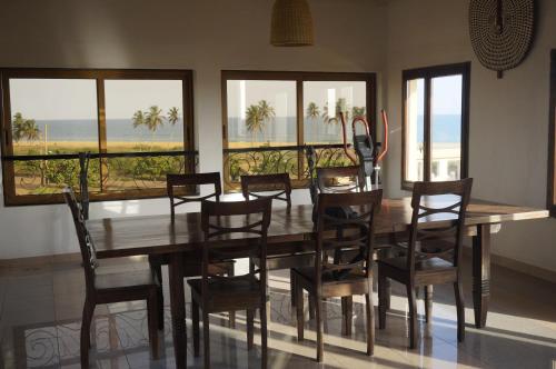 comedor con mesa, sillas y ventanas en Ramaya Auberge Espagnole, en Grand-Popo