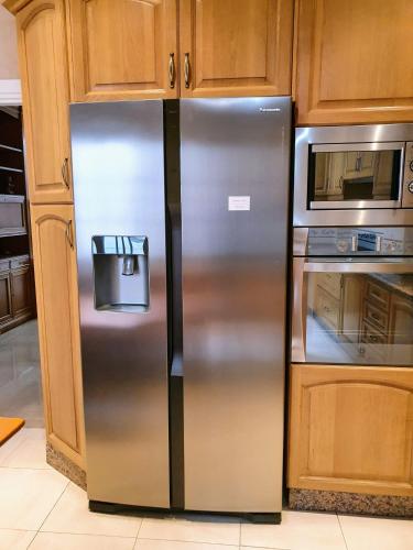 a stainless steel refrigerator in a kitchen with wooden cabinets at Triana Luxury Home in Seville