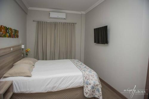ein Schlafzimmer mit einem weißen Bett und einem Fenster in der Unterkunft Hotel De Klomp in Carambeí