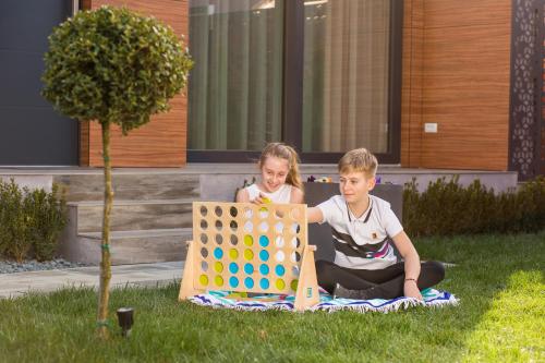 two children sitting on the grass playing with a large wooden game at DoubleL Studios in Bacău