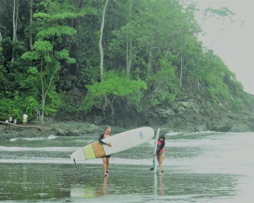 two people are standing in the water with their surfboards at Jaco Surf Beachbungalow in Jacó
