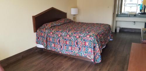 a bed in a room with a wooden floor at Family Inns of America - Mobile in Mobile