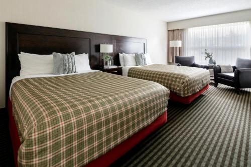 una habitación de hotel con 2 camas y una silla en Marmot Lodge Jasper, en Jasper