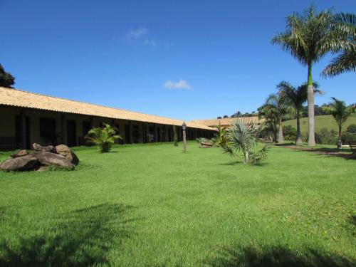 a building with palm trees and a field of grass at Hotel Fazenda Topada in Baependi