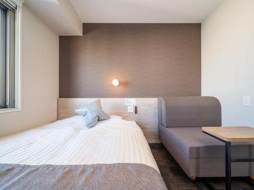 a small bedroom with a bed and a couch at Super Hotel Mitazono Sendai Airport in Natori