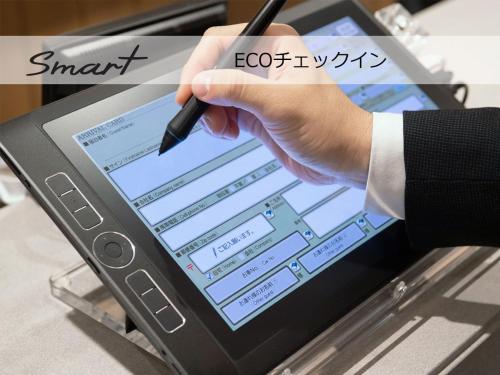 a person holding a pen in front of a tablet at Super Hotel Mitazono Sendai Airport in Natori