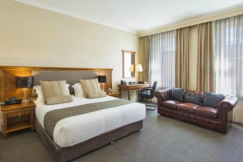 um quarto de hotel com uma cama e um sofá em The Grand Hotel Launceston (Formerly Clarion Hotel) em Launceston
