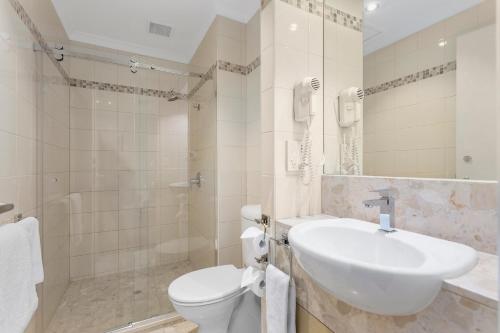 La salle de bains est pourvue d'un lavabo, de toilettes et d'une douche. dans l'établissement Clarion Suites Gateway, à Melbourne