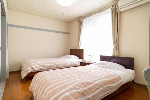 藤沢市にあるEnoshima Apartment Hotelのベッド2台 窓付きのベッドルーム1室