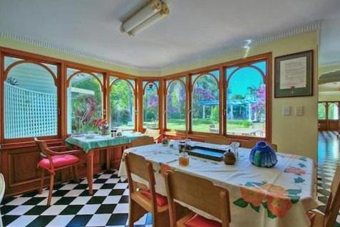 a dining room with a table and some windows at Melville House Bed and Breakfast in Lismore