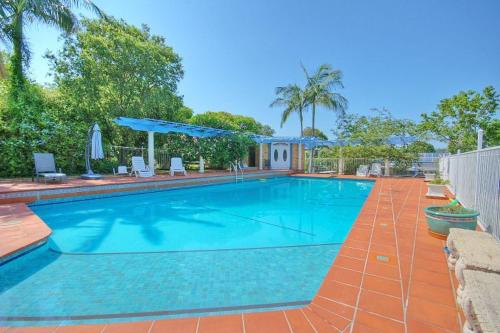 a large blue swimming pool with chairs and umbrellas at Melville House Bed and Breakfast in Lismore
