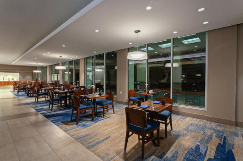 a dining room with tables and chairs and windows at Holiday Inn Los Angeles - LAX Airport by IHG in Los Angeles