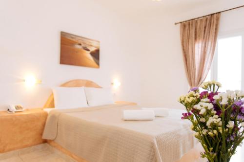 a bedroom with a bed with a vase of flowers at Nikos Hotel in Karterados