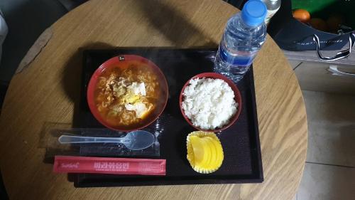 a tray with two bowls of food and a bottle of water at Manhatan Hotel 청주 in Cheongju