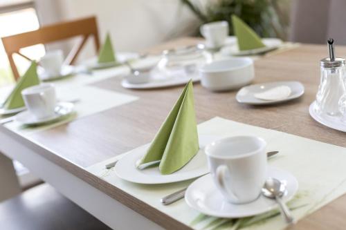 a wooden table with green napkins and cups on it at Deichhotel Grube in Dorum Neufeld