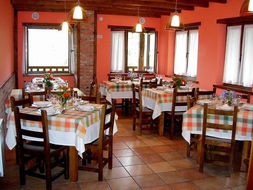 restauracja ze stołami i krzesłami w pokoju z pomarańczowymi ścianami w obiekcie La Posada de Cucayo w mieście Dobres