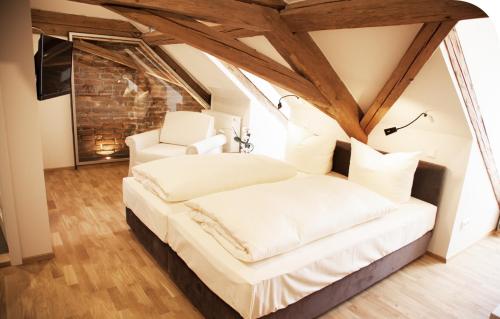 a bedroom with a white bed and two white chairs at Pension Kranzmayr in Sankt Wolfgang