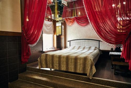 a bedroom with a bed with red drapes at Mirrors in Vinnytsya