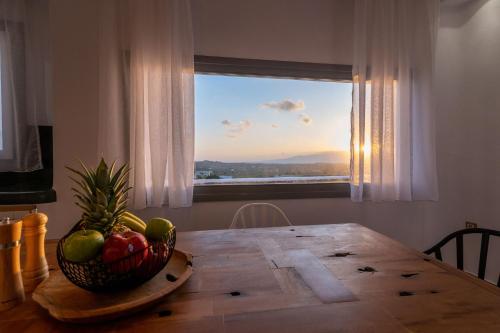 a dining room table with a bowl of fruit in front of a window at NAXIAN SUNSET VILLAS in Naxos Chora