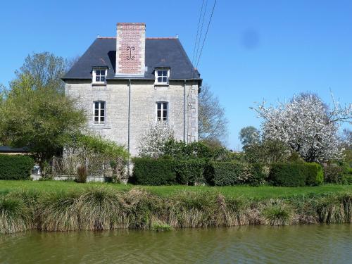 ein altes Haus am Ufer eines Flusses in der Unterkunft B&B L'Atelier du Presbytère in Saint-Maugan