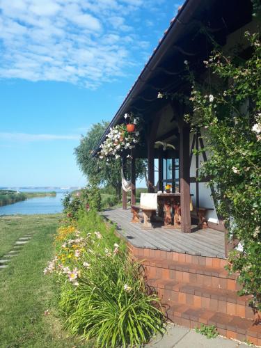 a building with a deck with a table and flowers at Svenceles 25 sodyba Namas su pirtimi ir krantine in Svenele