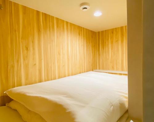 Bett in einem Zimmer mit einer Holzwand in der Unterkunft bnb+ Shinsaibashi in Osaka