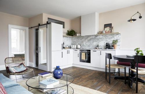 Luxurious 1 Bedroom Apartment - minutes from Angel Tube St. في لندن: مطبخ وغرفة معيشة مع دواليب بيضاء وطاولة