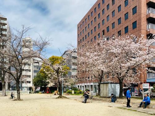 a group of people walking in a park with flowering trees at bnb+ Shinsaibashi in Osaka