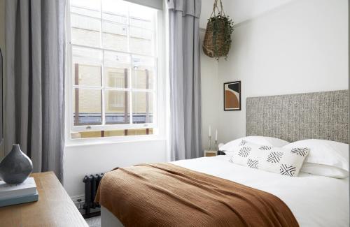 een witte slaapkamer met een bed en een raam bij Modern 1 Bedroom Apartment - minutes from Angel Tube St. in Londen