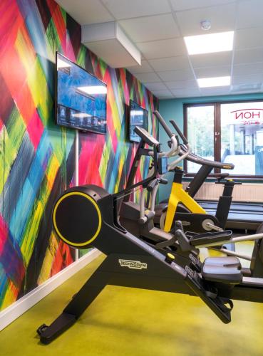 a gym with a treadmill and a colorful wall at Thon Hotel Slottsparken in Oslo