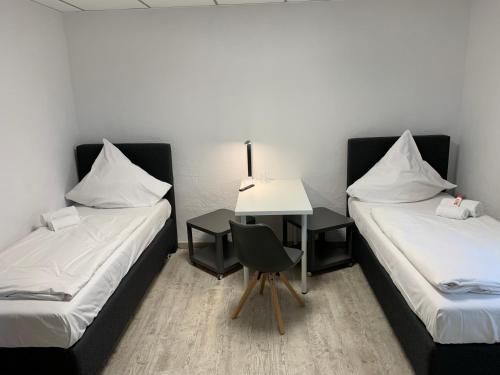 
a hotel room with two beds and a desk at Casino Hotel Neubeckum in Neubeckum
