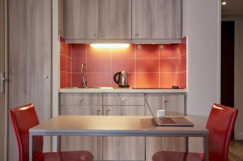 - une cuisine avec une table et un ordinateur portable dans l'établissement Aparthotel Adagio Aix-en-Provence Centre, à Aix-en-Provence