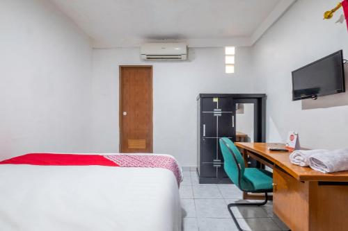 Schlafzimmer mit einem Bett und einem Schreibtisch mit einem Computer in der Unterkunft OYO Life 2391 Baladewa Residence Syariah in Karawang