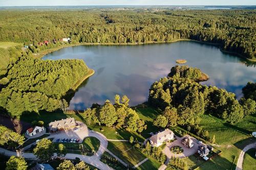 an aerial view of a lake with houses and trees at Folwark Hutta in Suwałki