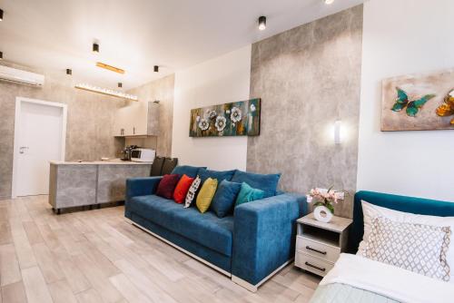 a living room with a blue couch and a kitchen at Royal Tower Luxurious Smart Residence (1) in Kyiv