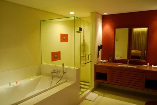 a bathroom with a tub and a shower and a sink at The Natsepa Resort and Conference Center in Ambon
