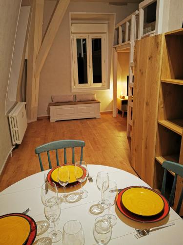 une table blanche avec des assiettes et des verres jaunes dans l'établissement Studio vue mer L échappée normande, à Saint-Pierre-en-Port