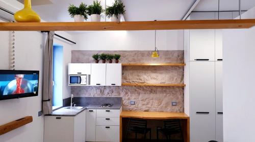 パレルモにあるMediterraneo Houseの白いキャビネットと壁掛けテレビ付きのキッチン
