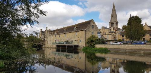 an old building with a church and a river at Riverside Stamford Stays in Stamford
