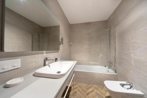 a bathroom with a sink and a toilet and a tub at Real Segovia Apartments by Recordis Hotels in Segovia