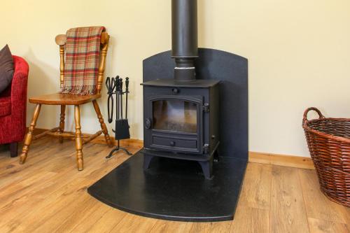 a wood stove in a living room with a chair at The Coach House, The Haywain, Bramling, Canterbury in Canterbury