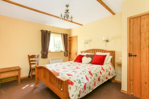 a bedroom with a wooden bed with red pillows at The Coach House, The Haywain, Bramling, Canterbury in Canterbury