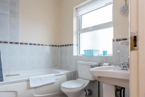 a white bathroom with a toilet and a sink at Ocean View - 2 Bedroom Townhouse in Bundoran