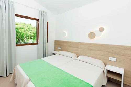 Habitación blanca con cama y ventana en HSM Club Torre Blanca, en Sa Coma