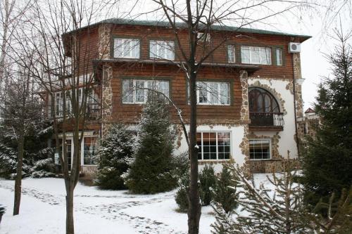 una grande casa di mattoni con la neve davanti di Hotel Orlinoye Gnezdo a Subottsi