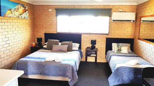 two twin beds in a room with a screen at Avlon Gardens Motel in Ballina