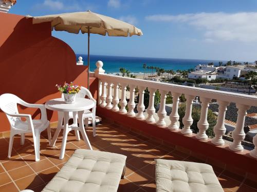 a patio area with chairs, a table and a balcony at Casa Roja in Costa Calma