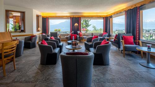 a waiting room with chairs and tables and windows at Hôtel Splendide in Crans-Montana
