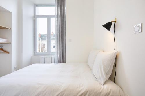 a white bedroom with a bed and a window at Résidence Colonel in Laval