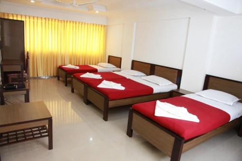a group of four beds in a room at Saiesh International Hotel in Mapusa